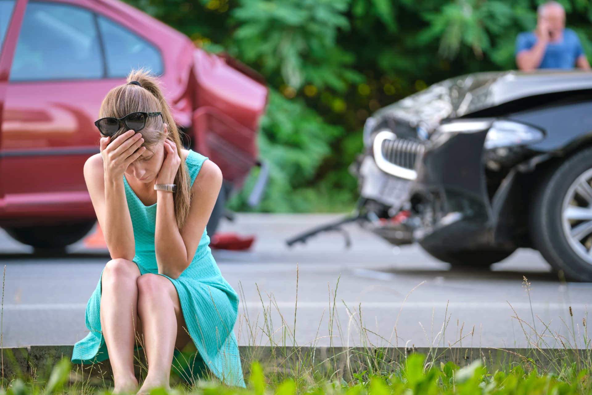 Stressed woman sitting on the roadside after a Sarasota car accident, showing the immediate emotional and physical impact of a crash